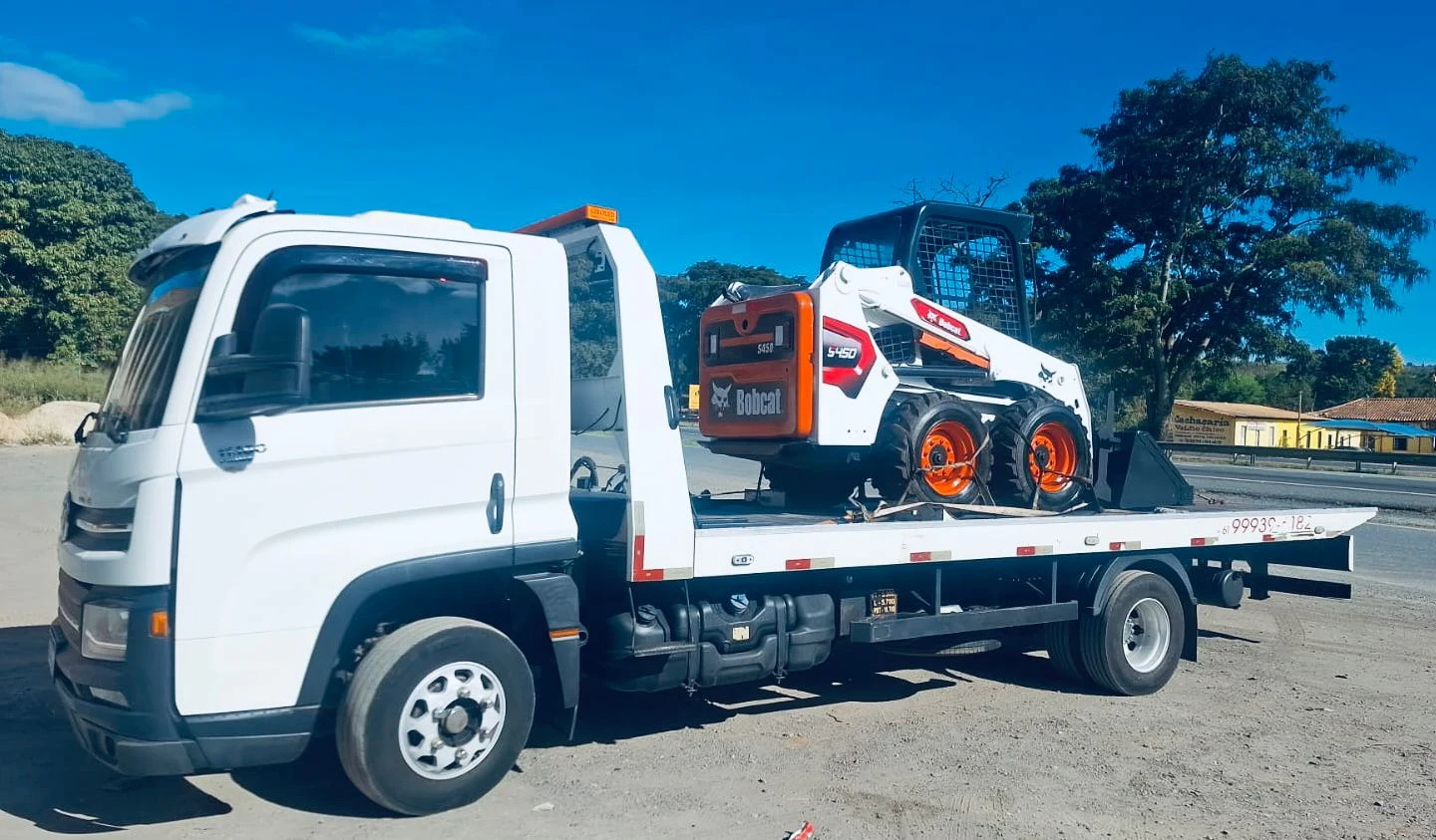 Caminhão guincho próprio da RM Locações transportando a Bobcat S450 no DF